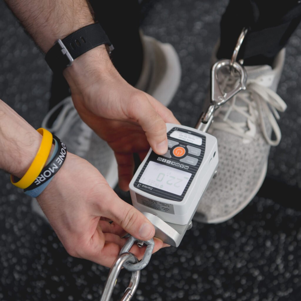 Physical therapist using a dynamometer to test patient's leg strength
