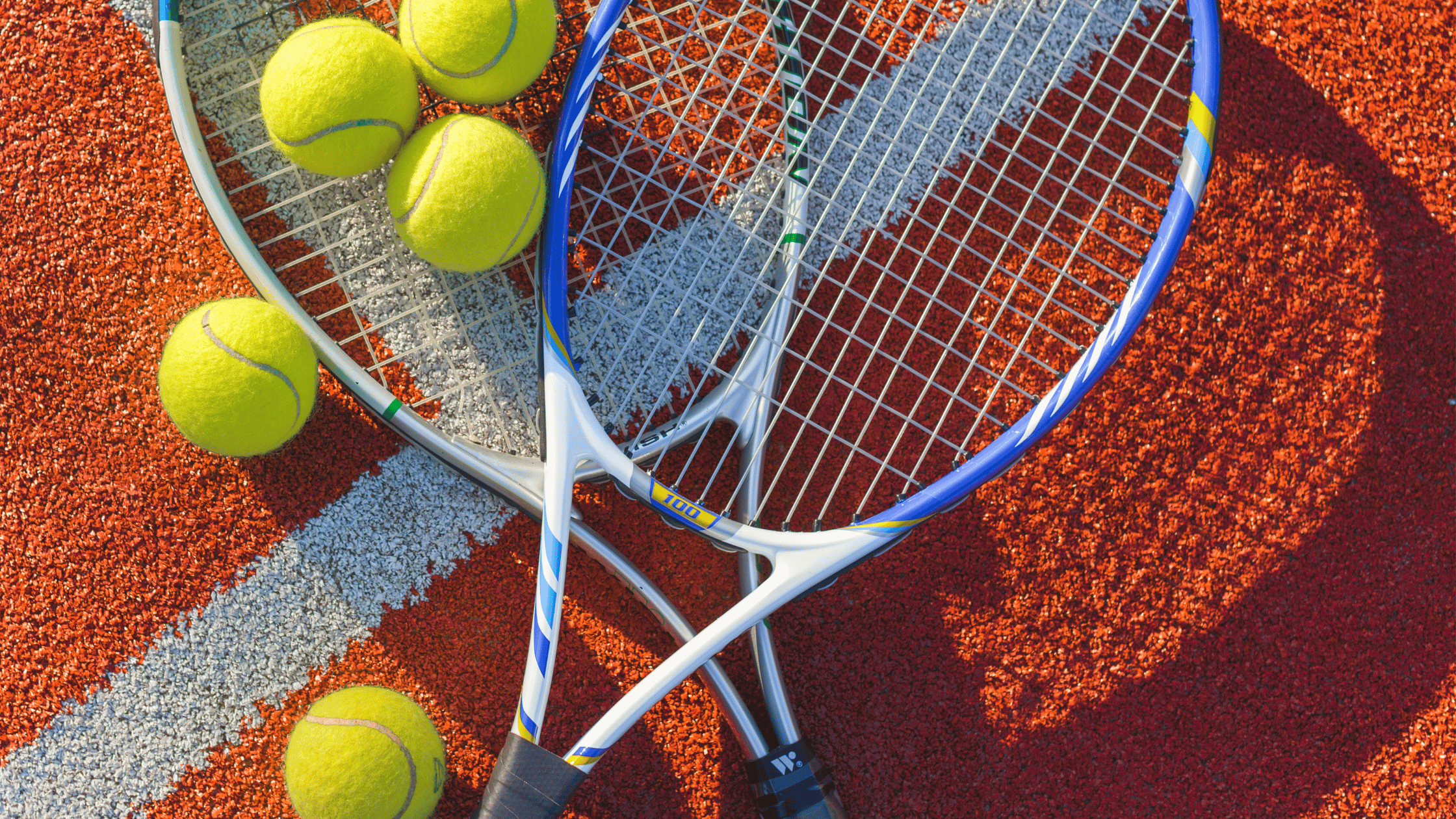 Tennis balls and rackets on a tennis court.